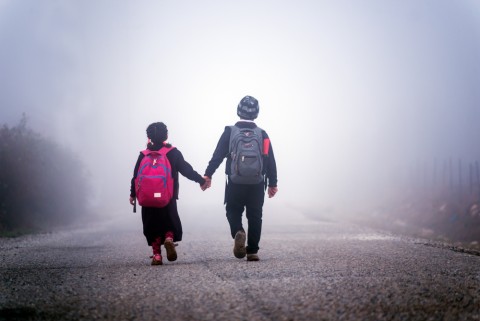 Children walk hand in hand towards the fog