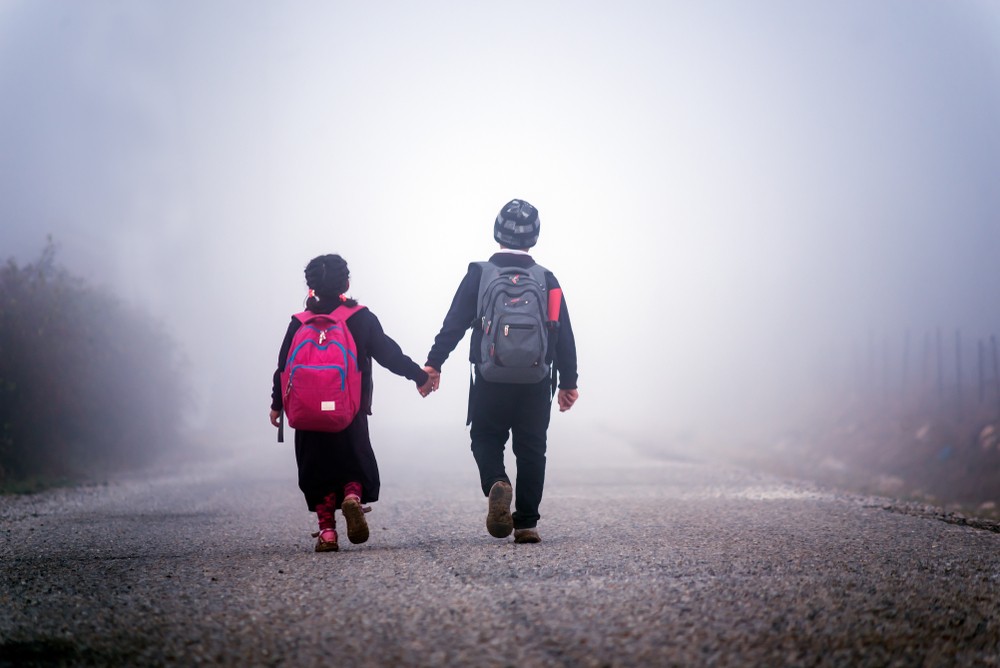 Children walk hand in hand towards the fog